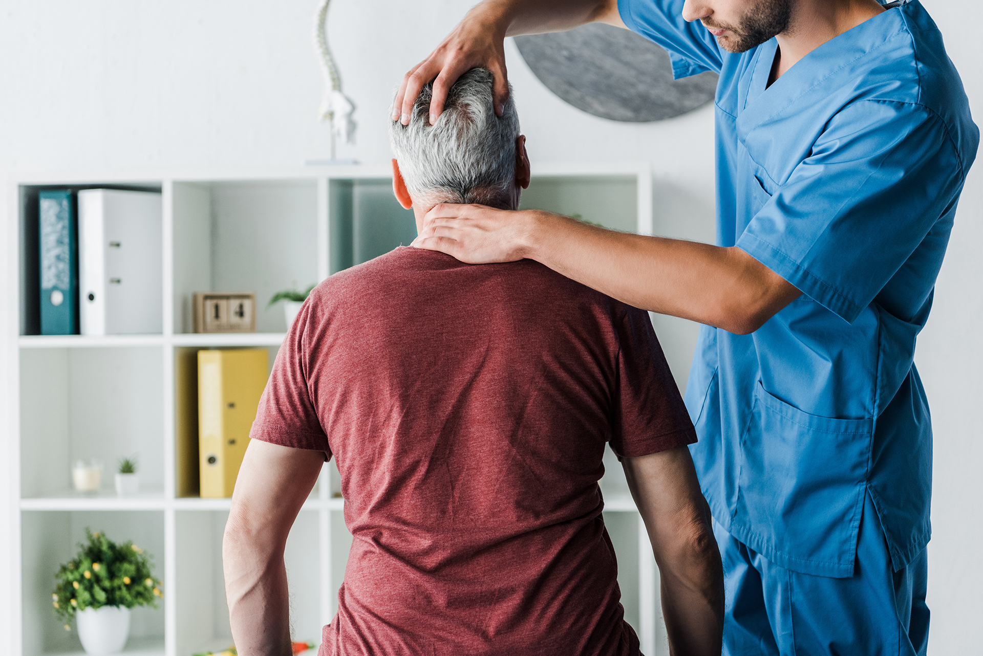 Experienced chiropractor holding a patient's head and neck to determine adjustment angles